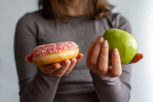 istock A girl holding an apple and a donut. 2189896815