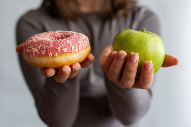 istock A girl holding an apple and a donut. 2189896818