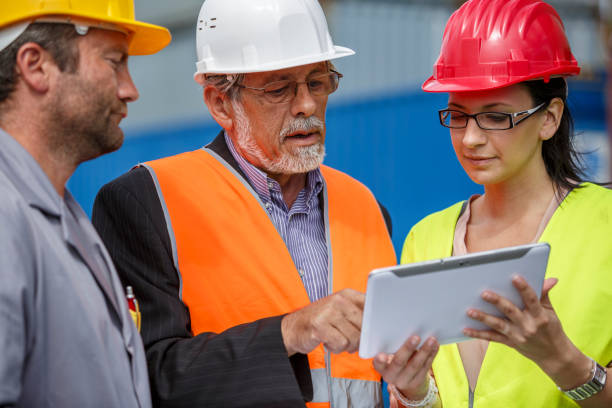istock Cargo dock with people using a tablet for logistics and stock management. Workers and a supervisor collaborating on freight operations, supply chain, and maintenance for an international shipping company. 2189903590