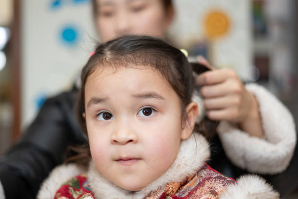 istock Young Asian mother tying daughter's hair 2189909738