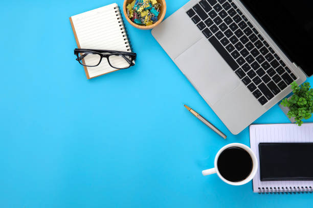istock Top view desk ,Modern office desk Workplace with laptop computer, coffee cup, glasses,notebook and office supplies for Working background concept. 2189913674