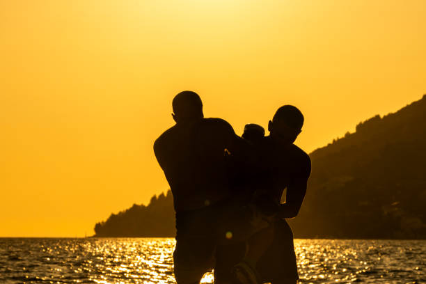 Palamos, Cataluña, Spain - April 21, 2011: One man in silhouette playing soccer on the sandy beach shoreline with waves rolling in and the sun sparkling on the water during a summer holiday in Palamos, Catalonia