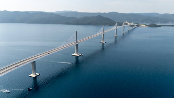 Aerial View of the Peljesac Bridge Reveals Its Impressive Structure Spanning Across the Sea,with Rugged Mountains in the Distance. The Vast Expanse of Water and Surrounding Landscapes Create a Striking Contrast to the Modern Engineering of the Bridge
