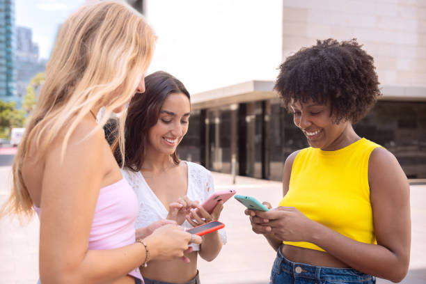 istock Three excited friends looking at a smartphone outdoors. 2189923029