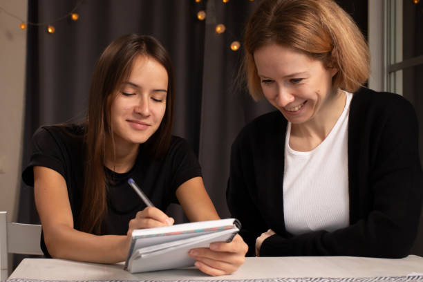 istock A mother and daughter share a moment writing in a notebook, sitting together at a table with warm decorative lighting 2189924420