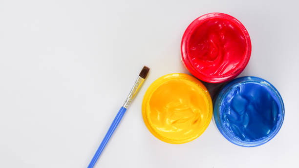 Three jars of red, yellow, and blue paint with a blue-handled brush on a white background. Perfect for art and creativity themes.