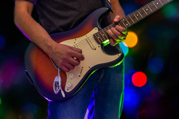 Close up of guitar player playing a solo on a dark background