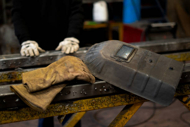 istock gloves and protective mask for a welder whose hands come out of the background with an iron 2189937440