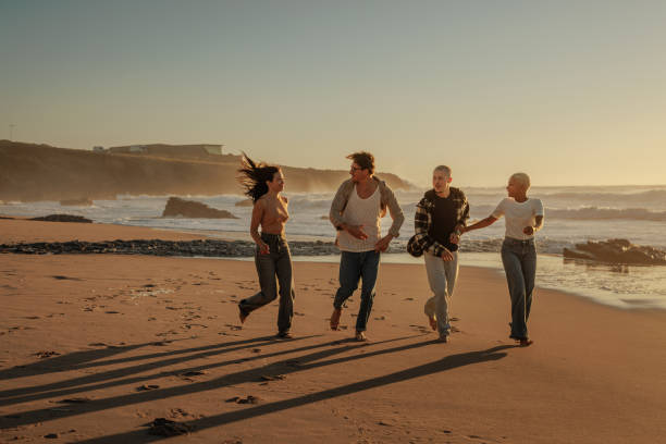 istock Happy friends running on the beach at sunset 2189938933