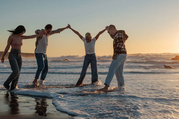 istock Friends holding hands and enjoying sunset on beach 2189938951