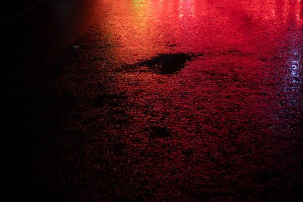 istock Red light on wet asphalt. Asphalt in a red glow in the evening. Empty parking space. 2189939749