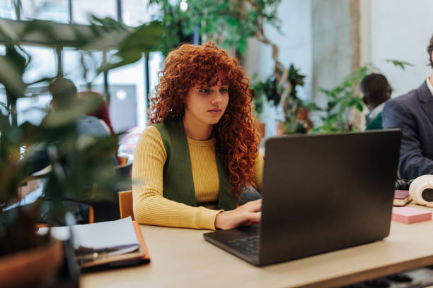 Young office worker typing on laptop in green workspace