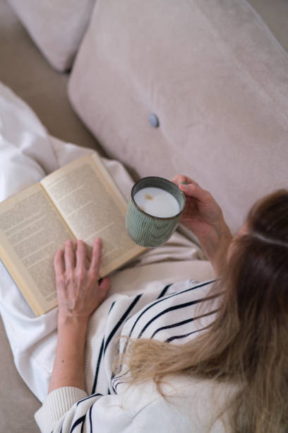 istock A woman is sitting on a couch with a book in her lap 2189941421