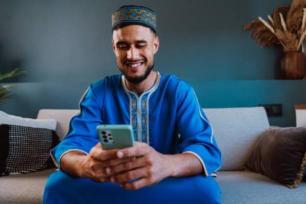 istock Moroccan guy with traditional outfit using smartphone. 2189941857
