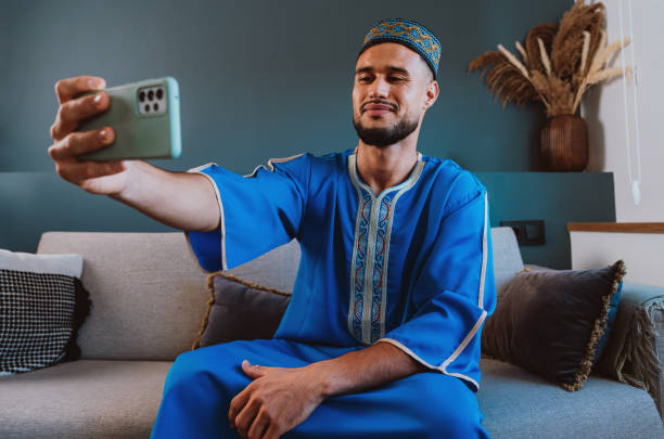 istock Moroccan guy with traditional outfit using smartphone. 2189941882