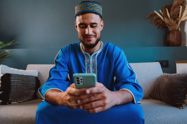 Moroccan guy with traditional outfit using smartphone.