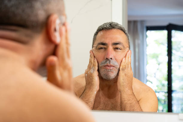 istock Middle-aged man massaging his face with soap in his hotel bathroom shortly before shaving 2189945032
