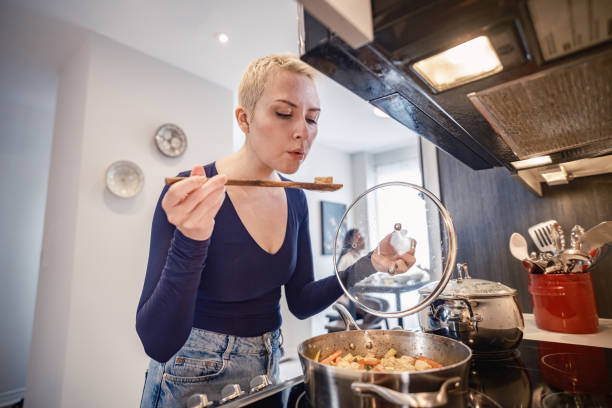 istock Young lesbian woman preparing vegetable curry in home kitchen 2189950299
