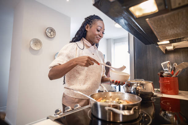 istock Young Black woman serving vegetable curry in home kitchen 2189950306