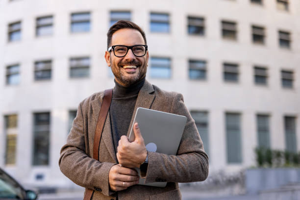 istock Smiling businessman holding laptop in urban setting 2189953142