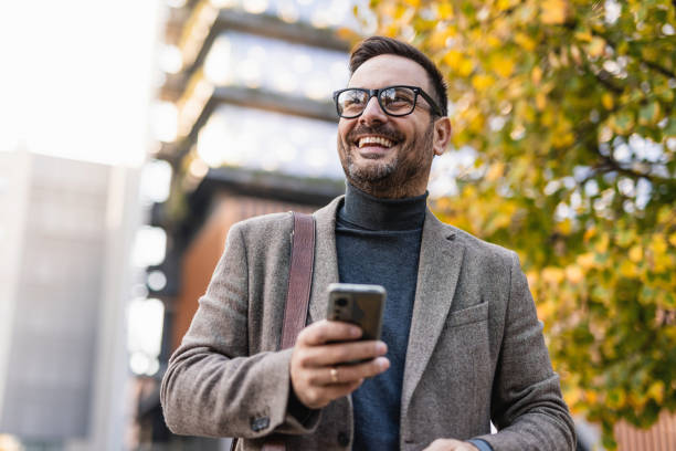 istock Smiling businessman using smartphone in urban setting during autumn 2189953147