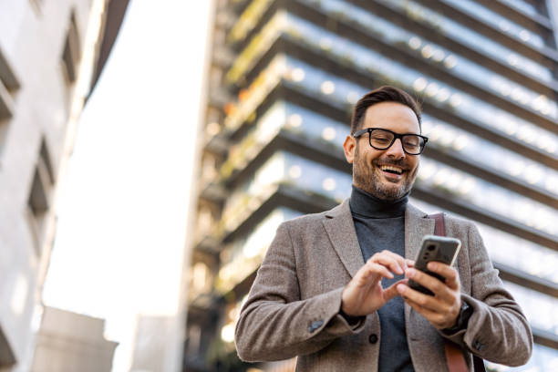 istock Smiling businessman using smartphone in city center 2189953154