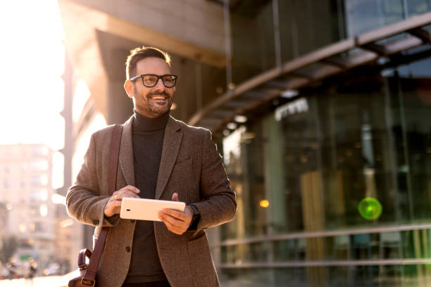 istock Smiling businessman using digital tablet while walking in city 2189953195
