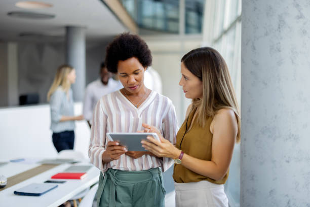 istock Diverse Female Professionals Engaged in Discussion with Digital Tablet 2189956417