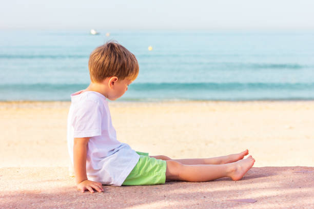 a boy sits on the sea coast, side view
