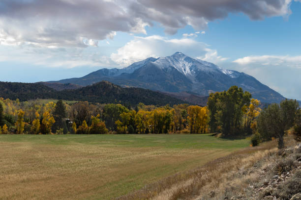 Mount Sopris comprises two peaks and lies within the Elk Mountain Range, a subrange of the Rocky Mountains in Colorado.  In this scene, the snow-capped mountain is bordered by bright autumn foliage, including the yellow aspen leaves for which the area is known.