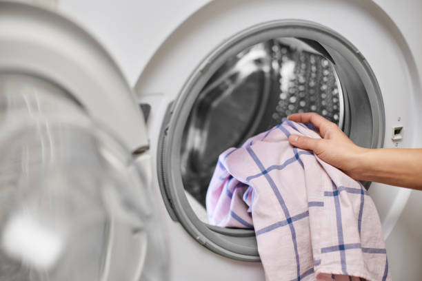 istock Woman putting clothes into the washing machine 2189985117