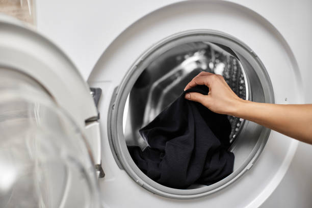 istock Woman putting clothes into the washing machine 2189985122