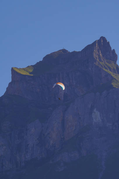 Paraglider in action against a rugged mountain cliff. Adventure seeker flying high. Scenic landscape perfect for outdoor sports enthusiasts and nature lovers.K
