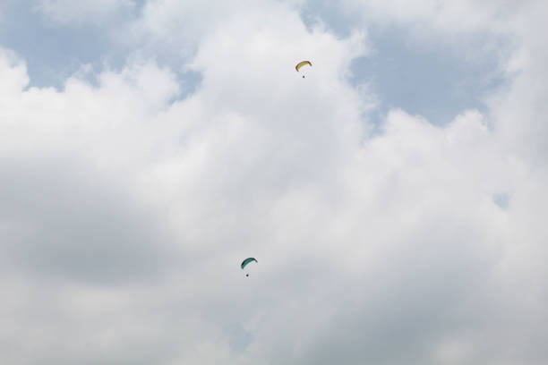 Two parachutes of paragliders with cloudy sky background