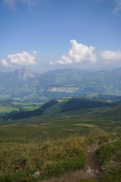 Scenic view of a green mountain ridge under a cloudy sky. Rolling hills and distant valleys create a majestic alpine panorama.K