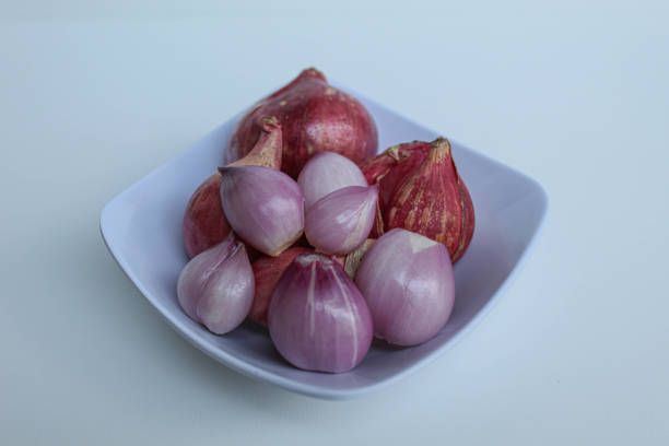 Red onion or shallots, before and after peeled, inside a bowl, isolated on white background