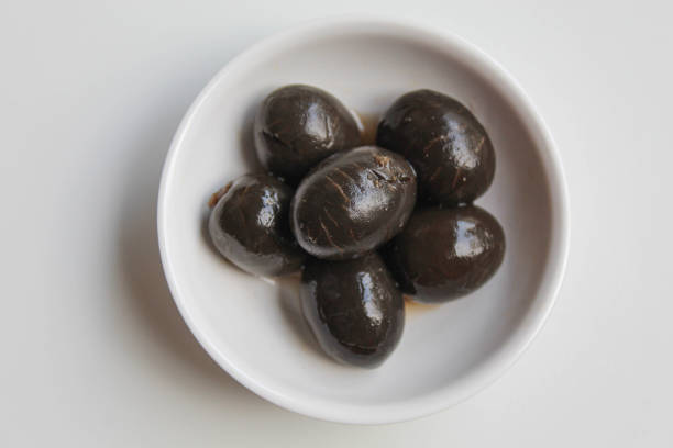 istock Table olives or fermented black olive, in small white bowl, isolated on white background, flat lay or top view 2190001768