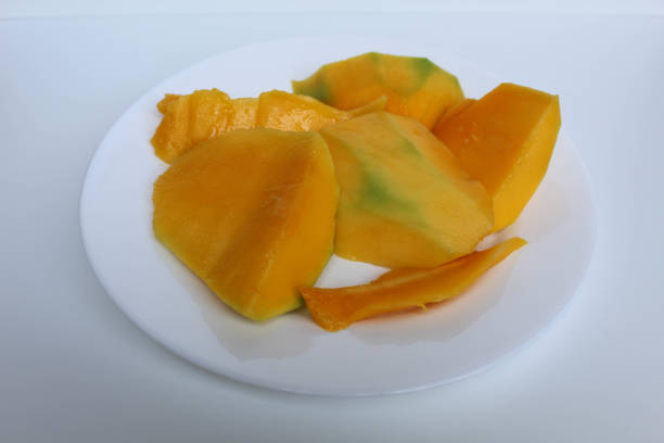 Fresh yellow mango slices, on white plate, isolated on white background