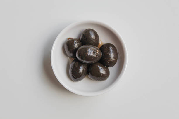 istock Table olives or fermented black olive, in small white bowl, isolated on white background, flat lay or top view 2190004020