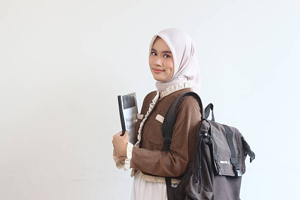 istock A Smiling Muslim Woman Student Ready for Class, Carrying Books and Backpack Against White Background 2190004764