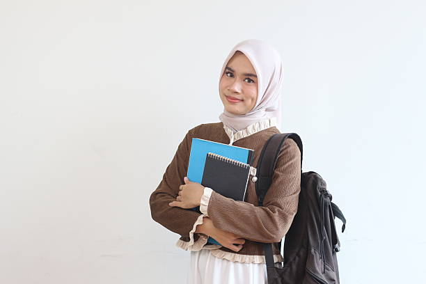istock A Smiling Muslim Female Student Holding Books and Backpack Against White Background, Ready for Education 2190004887