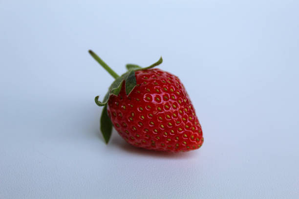 istock One red strawberry with green stem, isolated on white background 2190005744