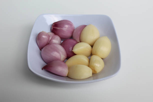 Peeled shallots and garlic, in small bowl, isolated on white background