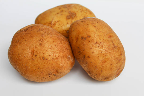 Three potatoes unpeeled, isolated on white background