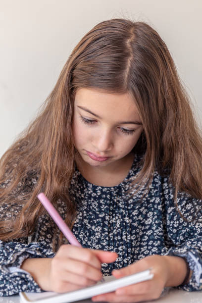 istock A sad girl draws in a notebook. School homework at home. 2190013515