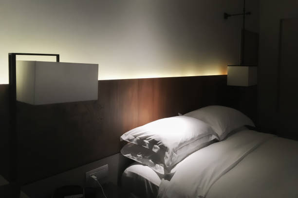 Interior of a contemporary cozy bedroom with furniture in earthtone colour scheme a cozy armchair, and a small writing desk, all bathed in natural sunlight filtering through sheer curtains.