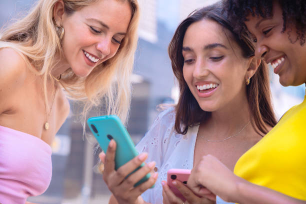 istock Three excited friends looking at a smartphone outdoors. 2190017910