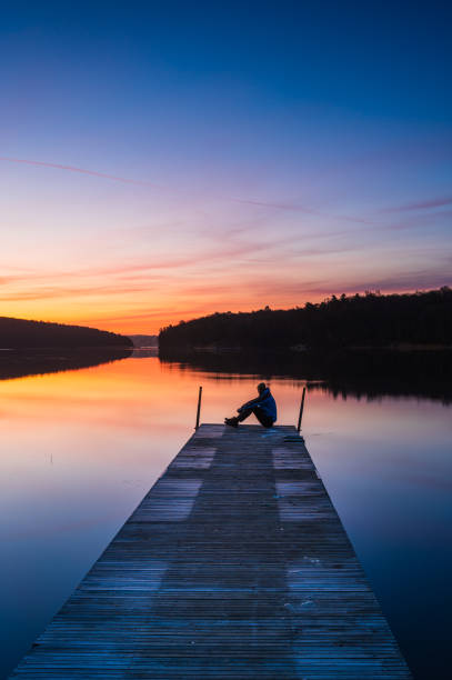 istock Man sitting on jetty at sunrise 2190023554