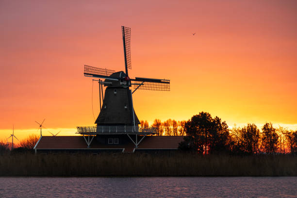 istock Idyllic Dutch windmill by the water under a golden morning sky 2190024884
