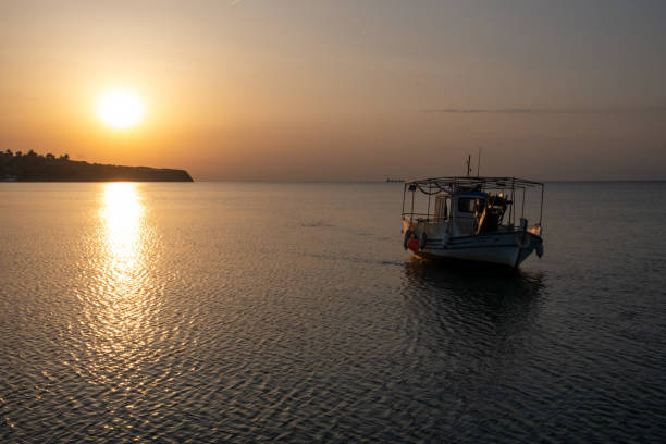 Sunset over Greek bay with fishing boat